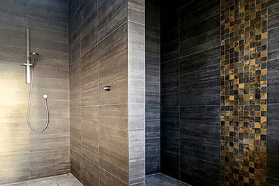 Dark bathroom tiles on the wall with mosaic and stone style floor tiles